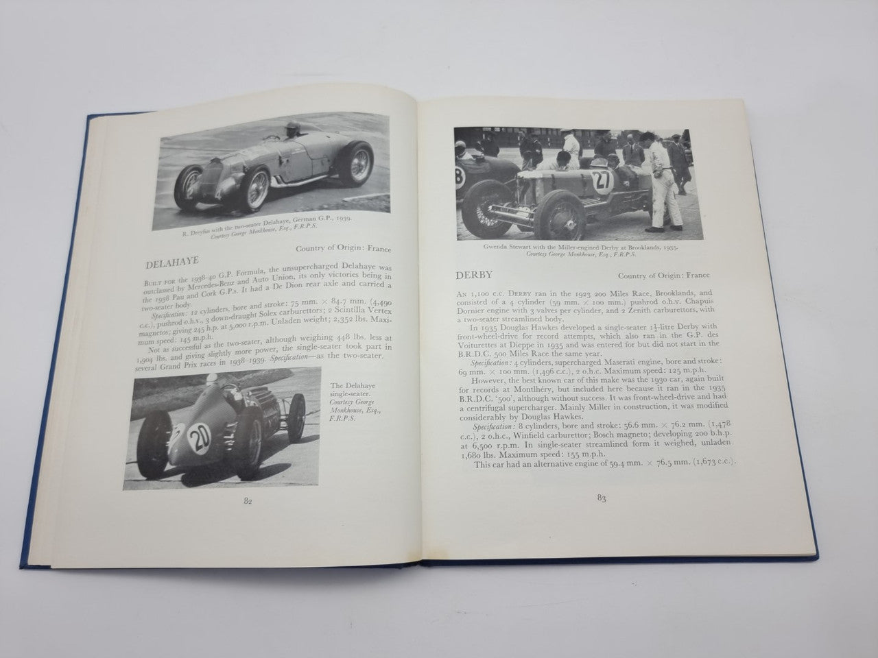 Open racing cars history book with vintage race car photos and detailed text blocks