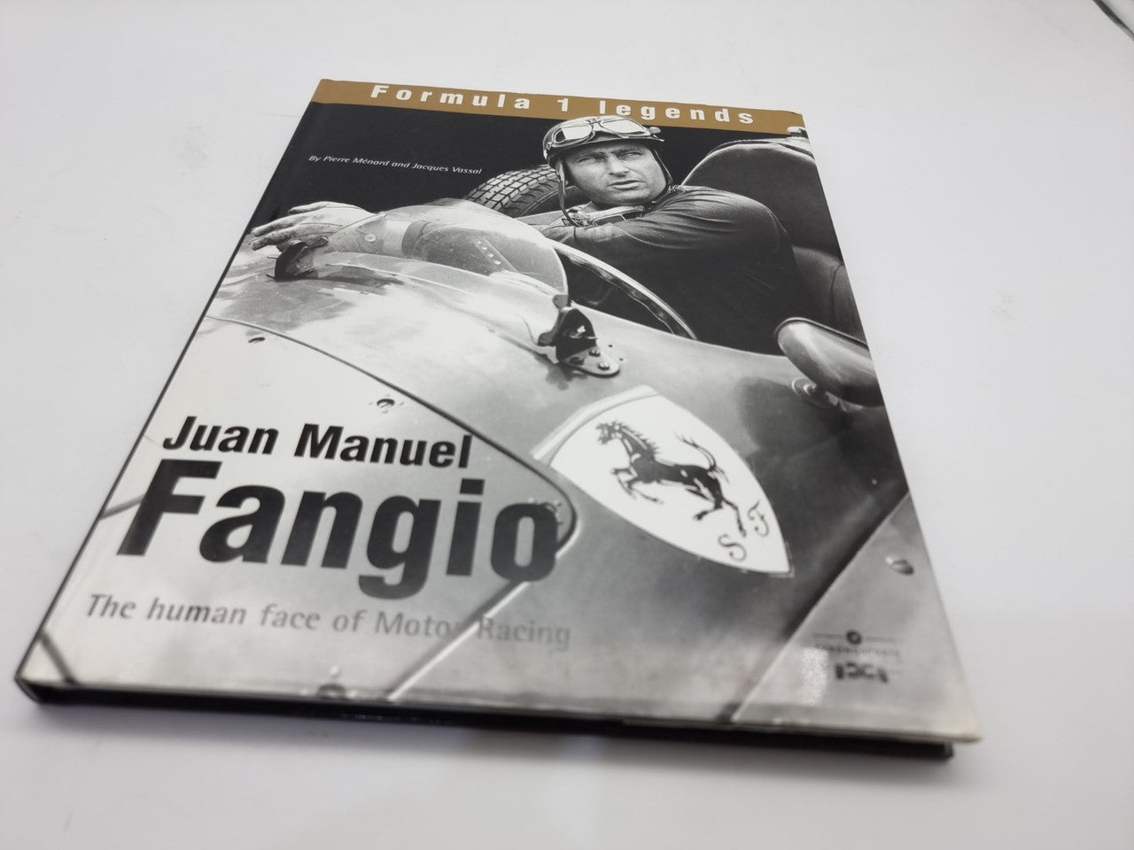 Motorsport history book with Fangio portrait on race car cover