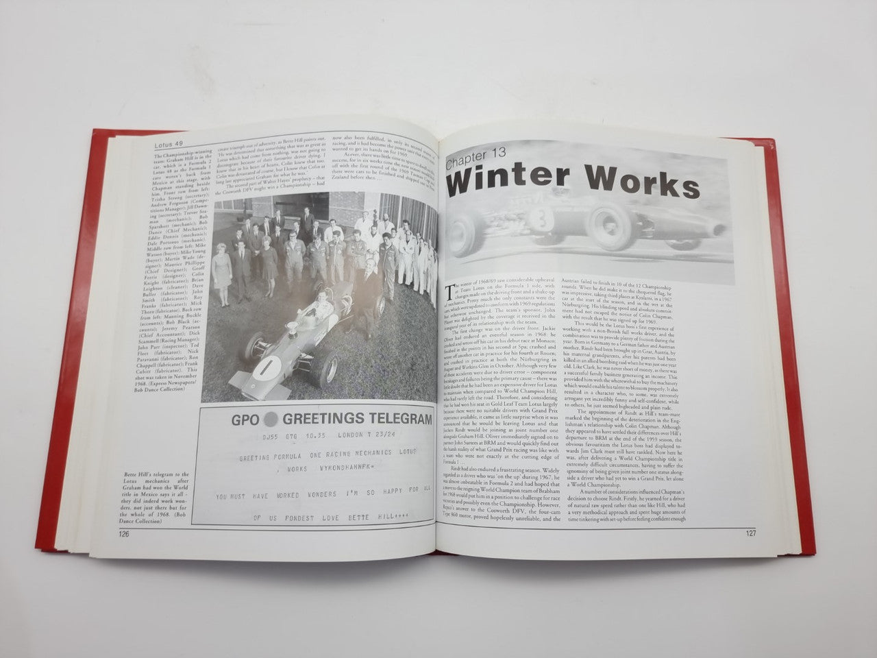 Open hardcover book with red cover, black text and racing photos on both pages