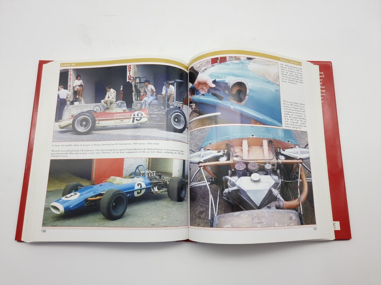 Open hardcover book with red cover, photo pages showing a blue race car and cockpit