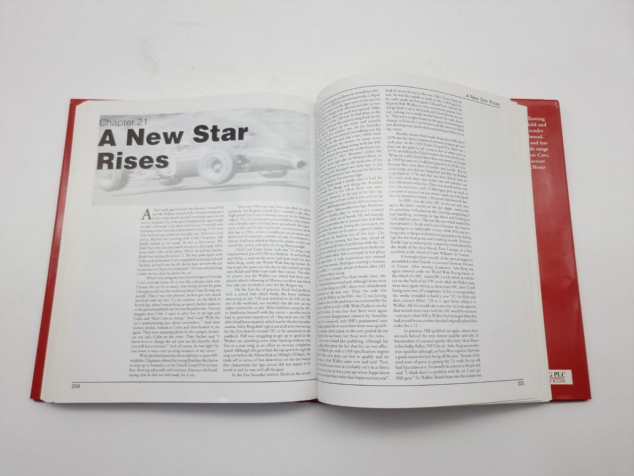 Open hardcover book with red cover, large heading and two-column text with a car photo