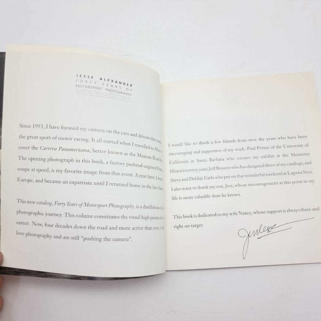 Motor racing photography book open to text pages with a visible signature