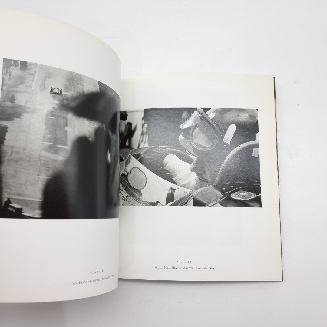 Motor racing photography book open with black-and-white driver seated in a race car