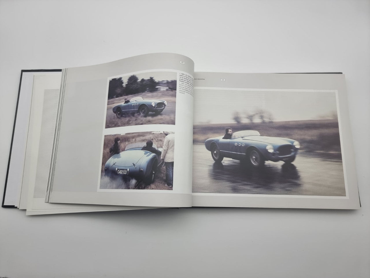 Signed sports car photo book open, showing two classic cars on track