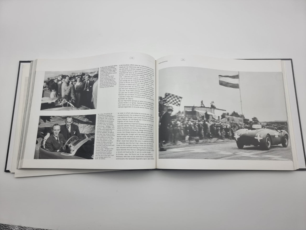 Signed sports car photo book open, showing crowds and a vintage race car