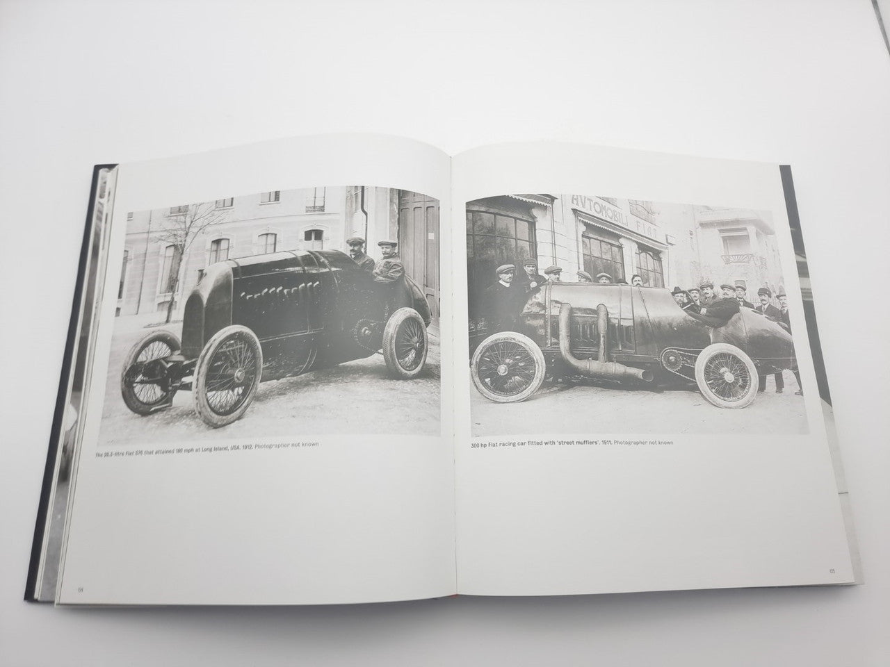 Open motor racing photo book showing two vintage cars in black and white