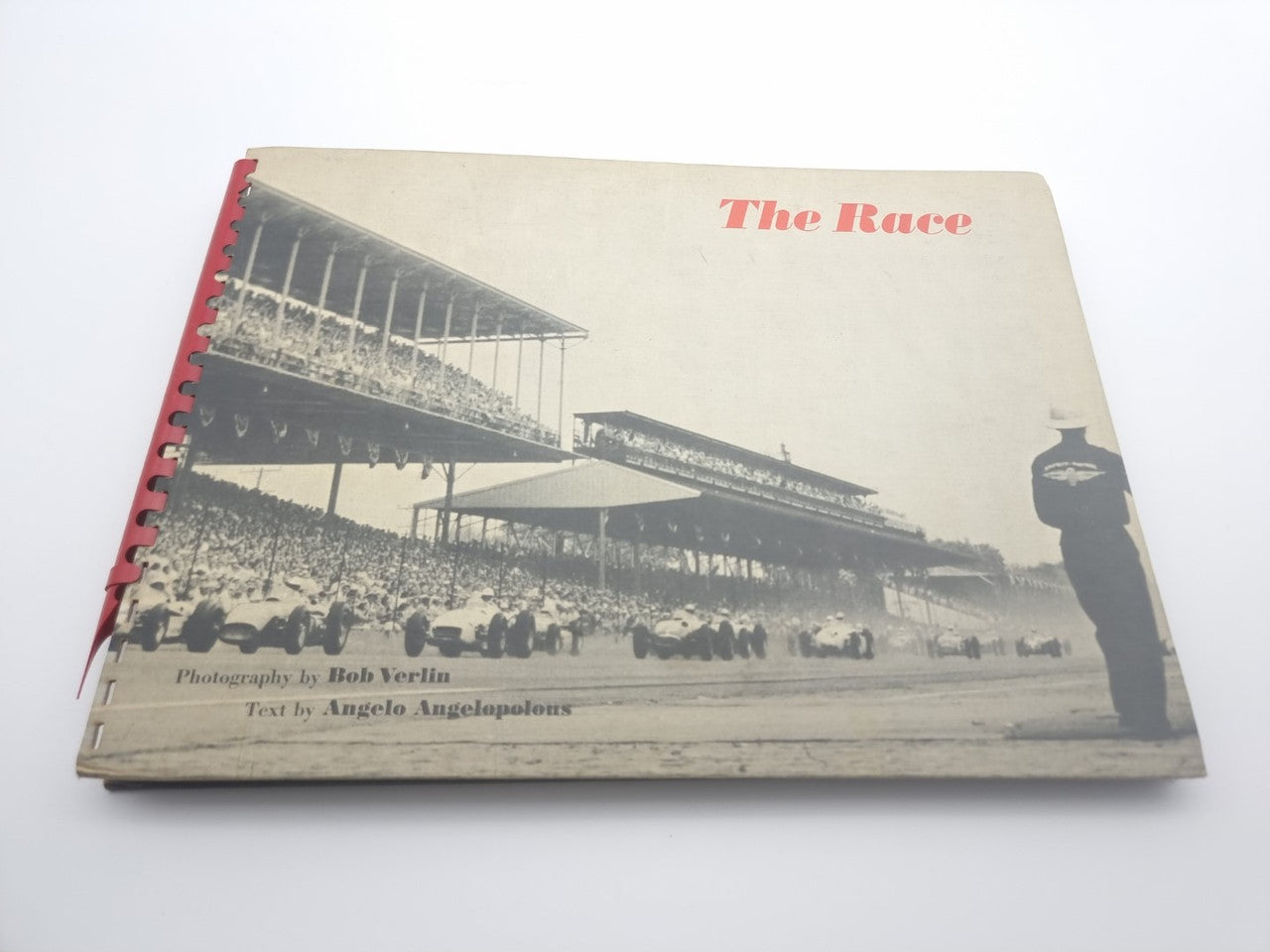 Vintage photo book cover with race stadium image and red spiral binding.