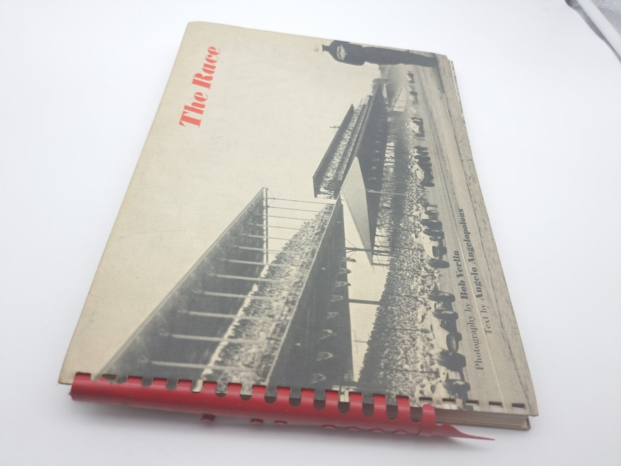 Vintage photo book cover showing race track stands and red spiral binding.
