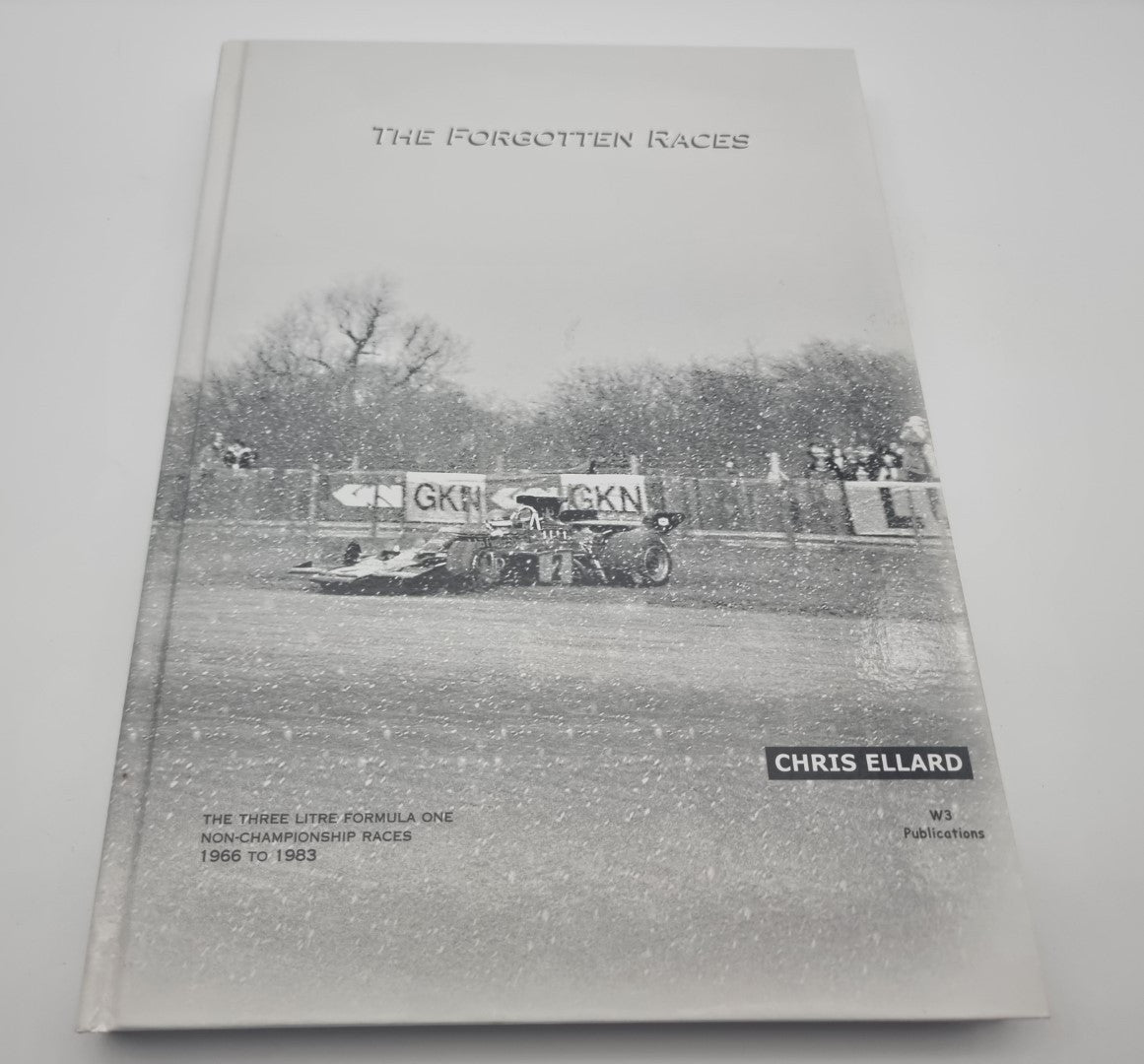 Race history book front cover with title, driver and vintage race car on track