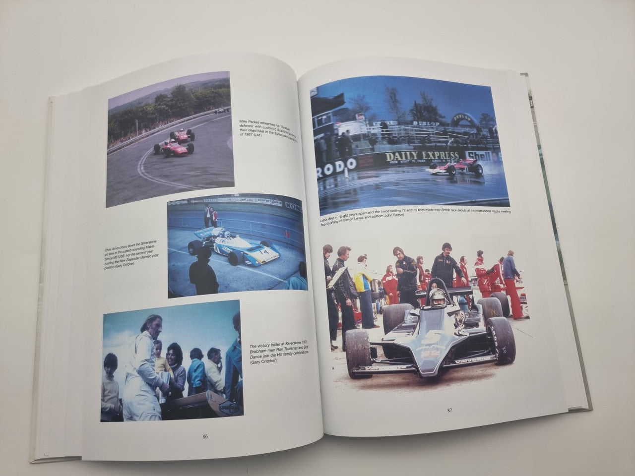 Race history book open, pages with four color track photos and team lineup image