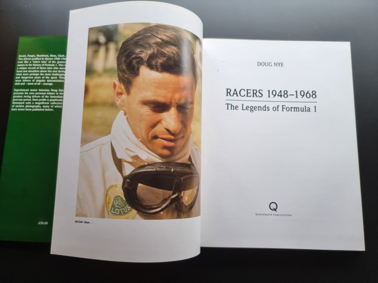 Racing book open to a page with a driver portrait and title page behind it.