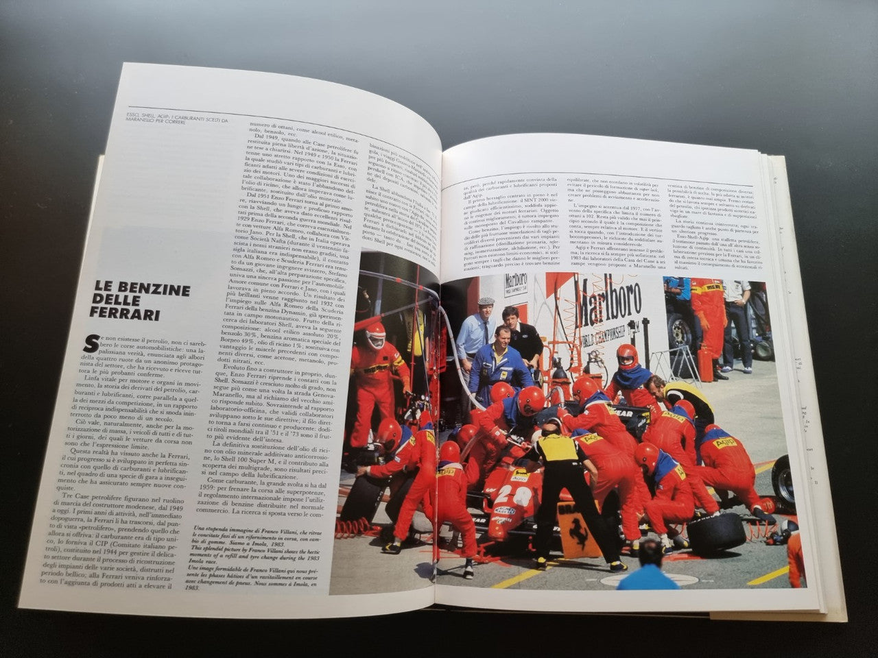 Open year book with pit crew group photo beside red race car