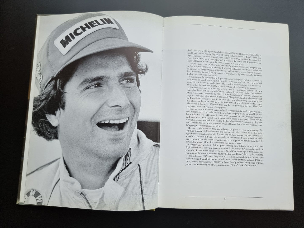 Open motorsport book pages with black-and-white portrait wearing a MICHELIN cap