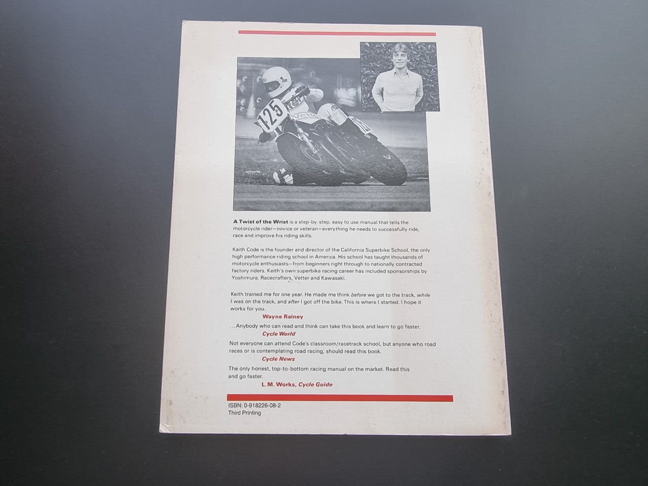 Open book page with small motorcycle photo, dense text block, and red header lines