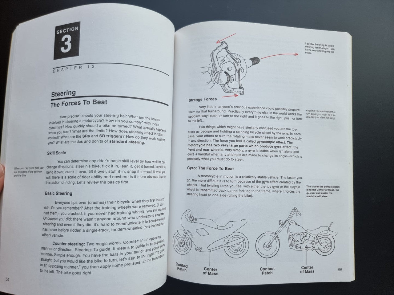 Motorcycle riding guide paperback, open spread with Steering chapter text and spring diagram.