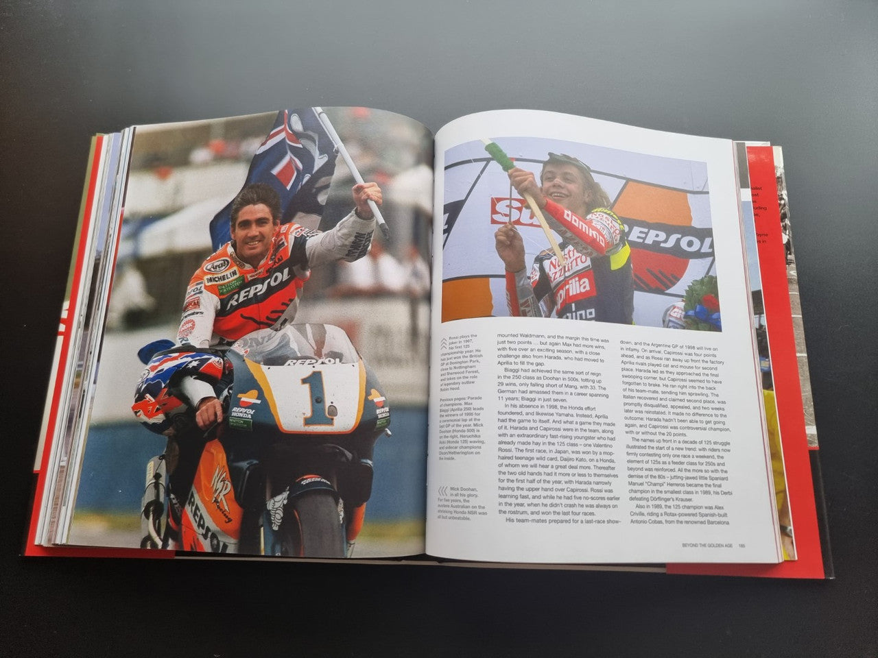 Motorsport history book, open spread with two color motorcycle racer photos and captions