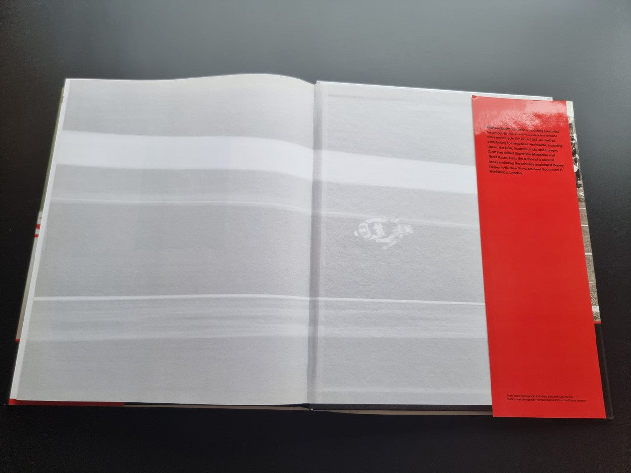 Motorsport history book open to blank pages with a red vertical panel on the right