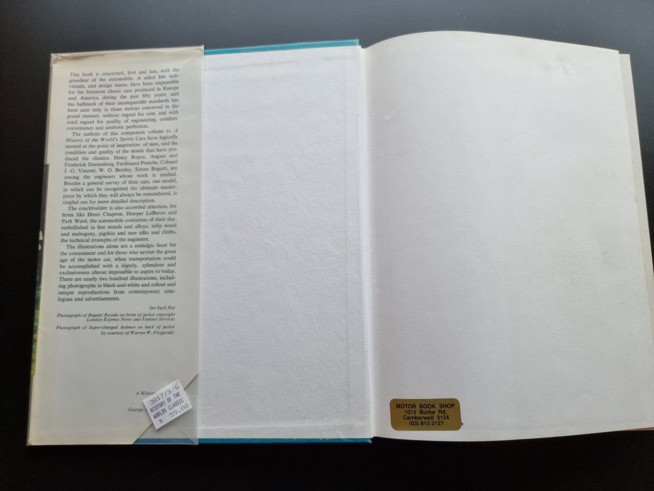 Classic car history book open to blank pages with small attached card