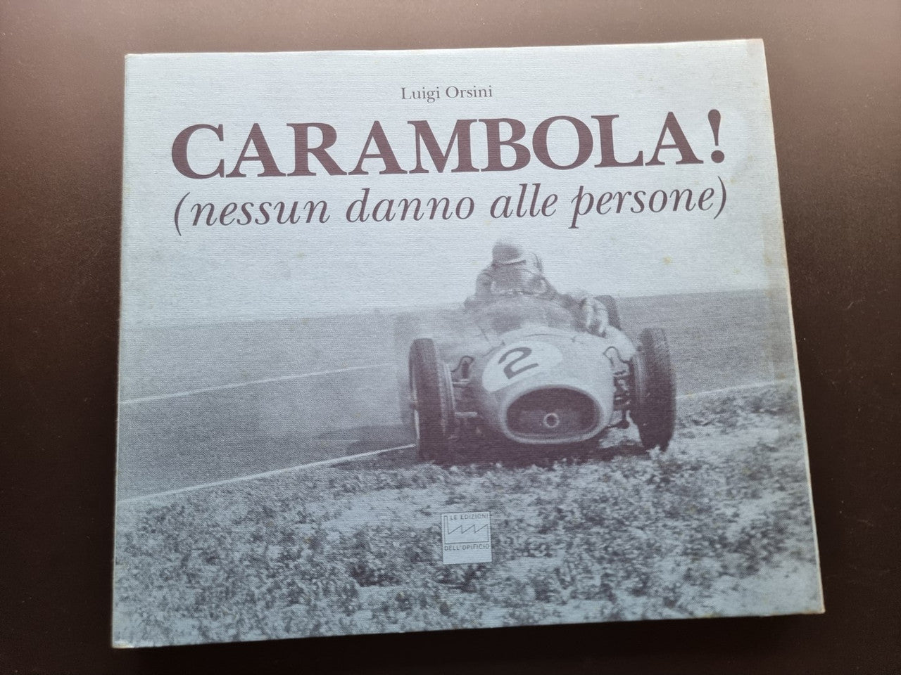 Book cover with title text and a vintage race car photo beneath