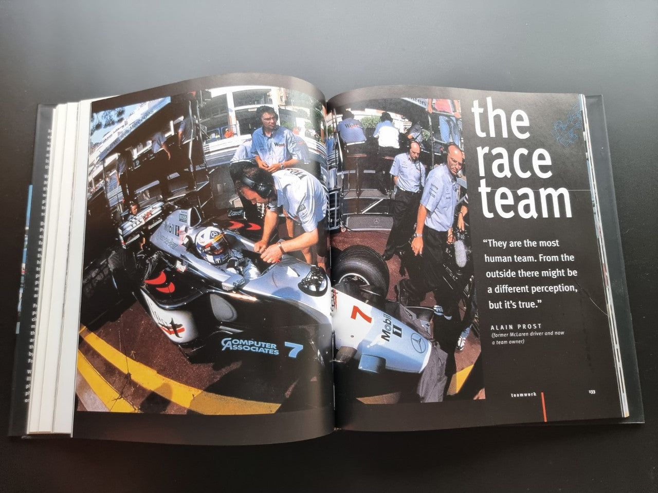 Open biography book with racing team photos and car cockpit image spread