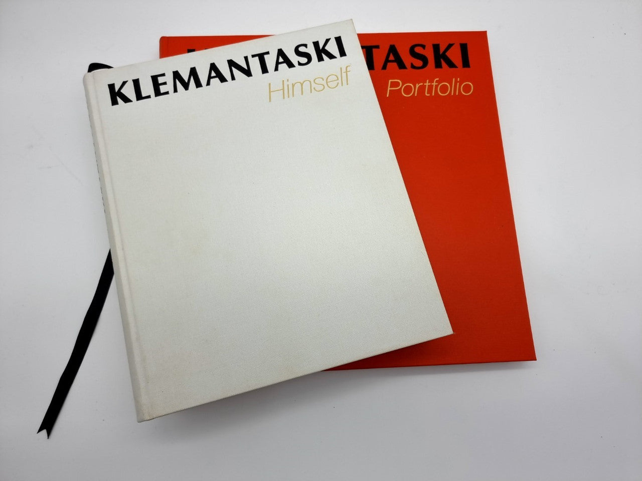 Photo portfolio book with white cover and red back, tied with black ribbon
