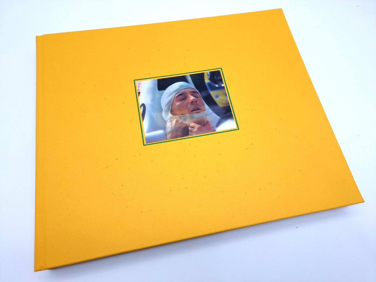 Signed motorsport book cover with yellow background and small portrait photo