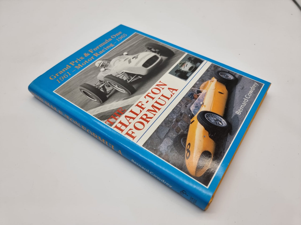 Motor racing book lying at an angle with blue border and F1 car photos