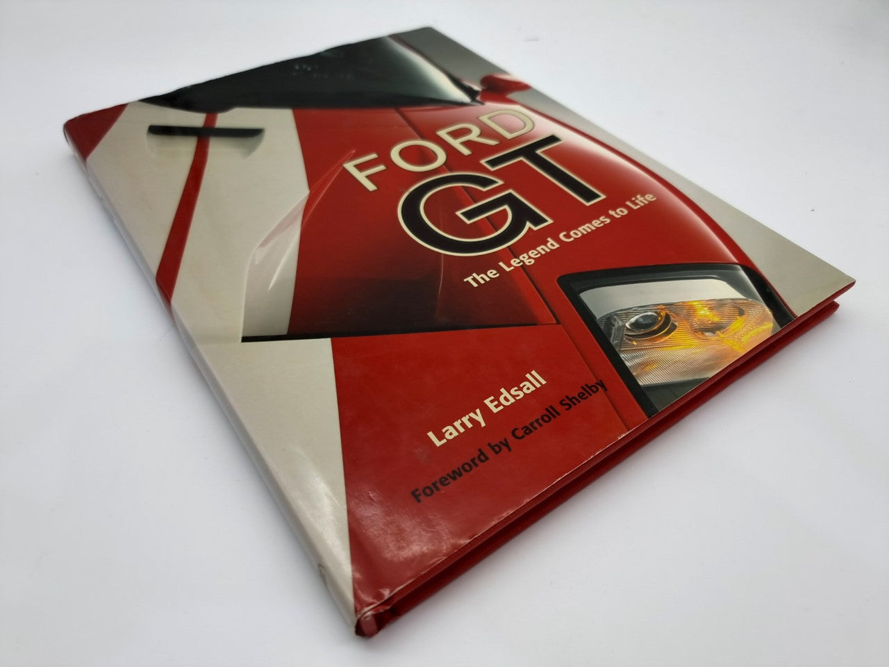Hardcover Ford GT book with red-and-white cover and car headlight photo