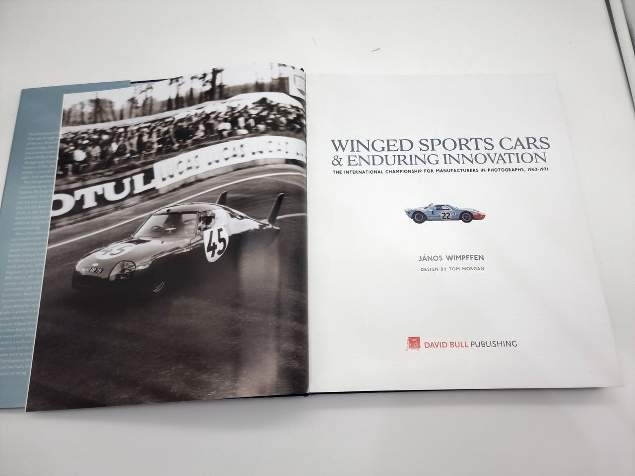Open book spread with black-and-white race car photo left page and title page right
