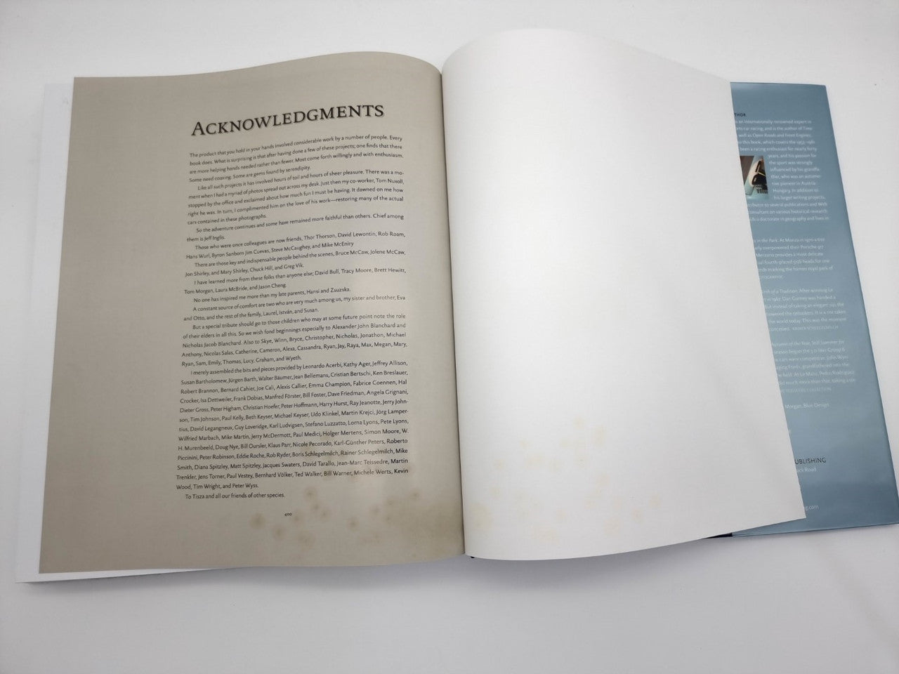 Signed book open to acknowledgements page with dense text and a blank facing page