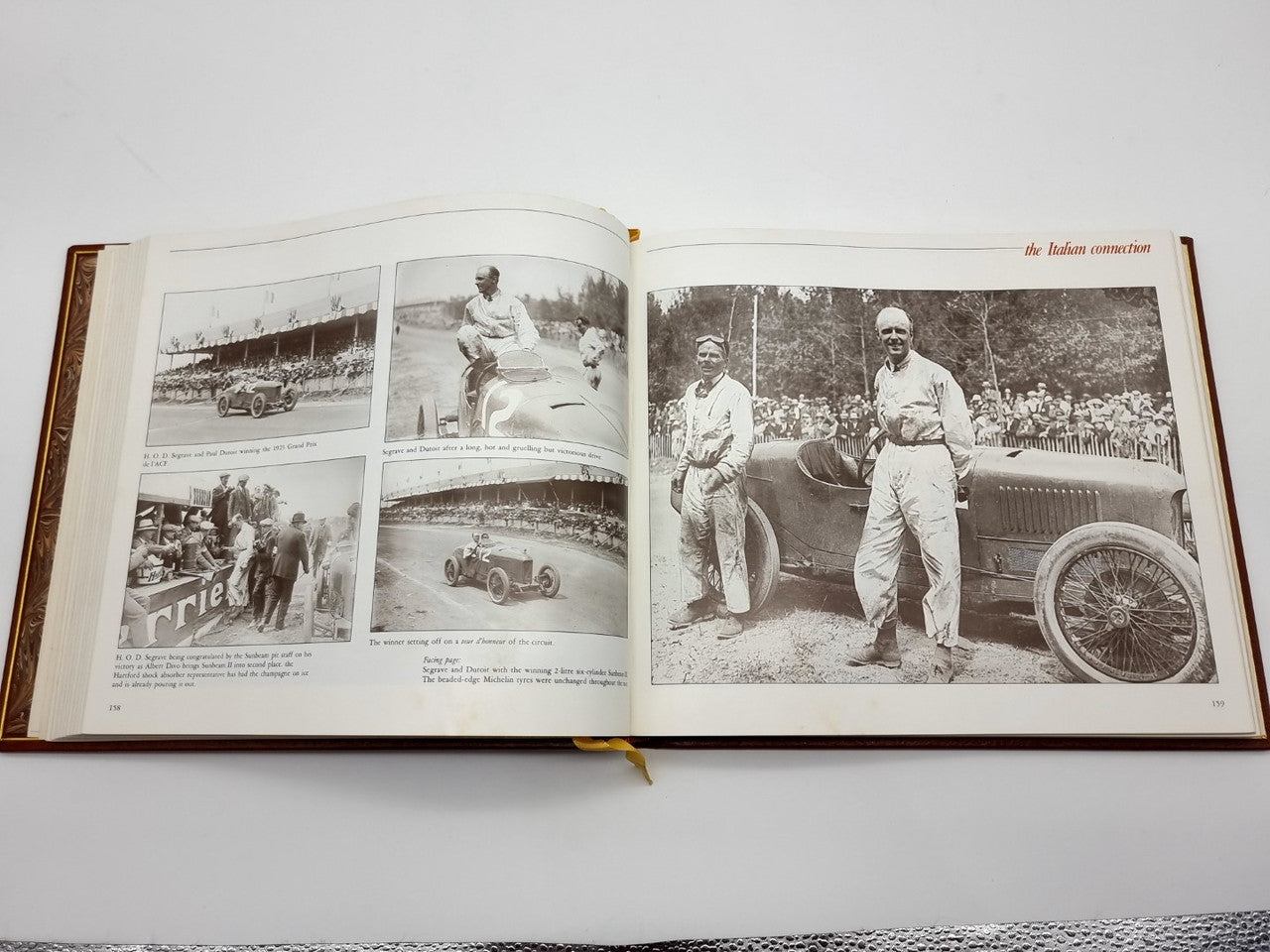 Open brown leatherbound book with black-and-white racer and crowd photos