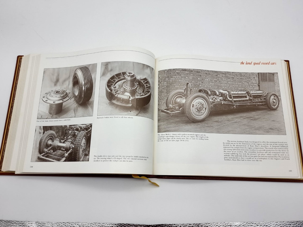 Open brown leatherbound book with black-and-white race car photo spread