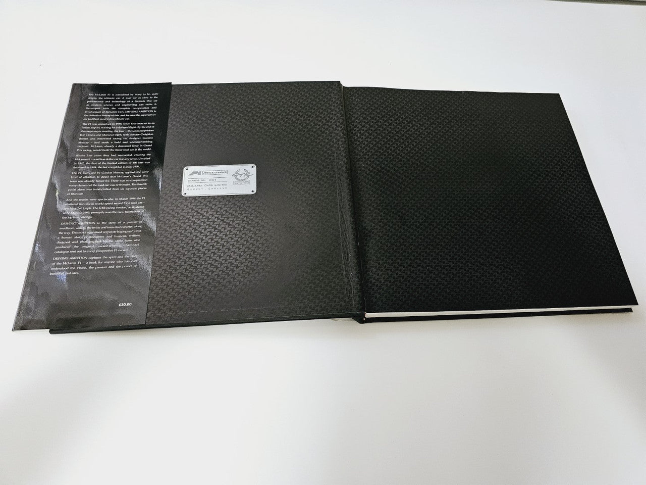 Closed hardcover book with dark textured cover and a white label sticker