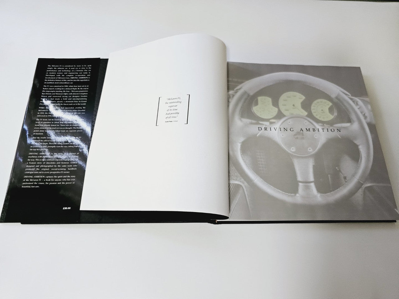 Open hardcover book with black and white pages and a steering wheel photo