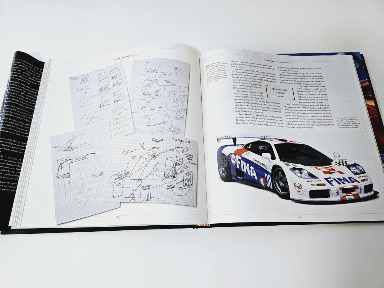 Open book with white schematic pages and a color race car photo