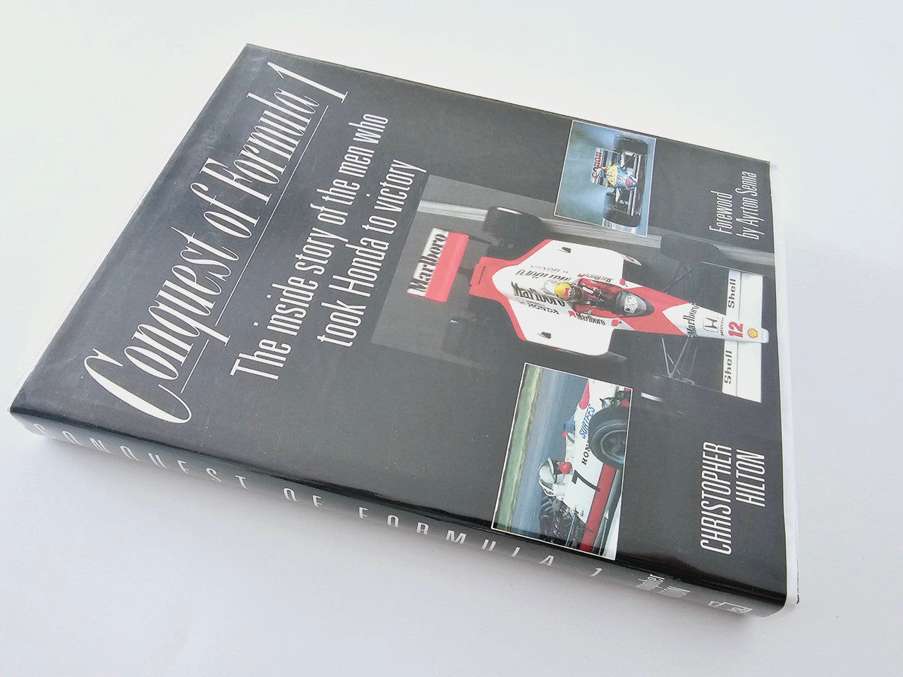 Hardcover book with dark cover, colorful race images, and white title text