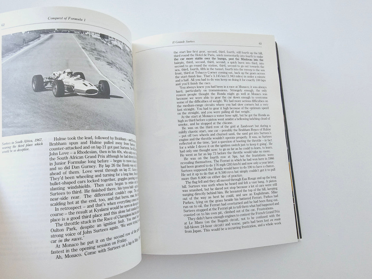 Open book with text pages and black-and-white Formula 1 race photo