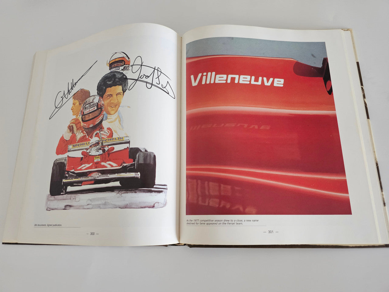 Ferrari racing book open pages with illustrations and a red car close-up.