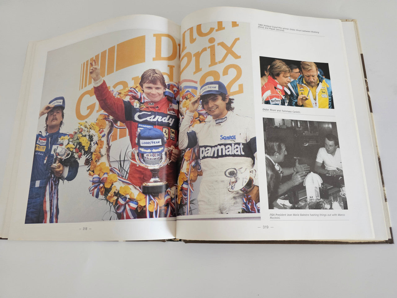 Ferrari racing book open pages with colorful podium scene and a black-and-white photo.
