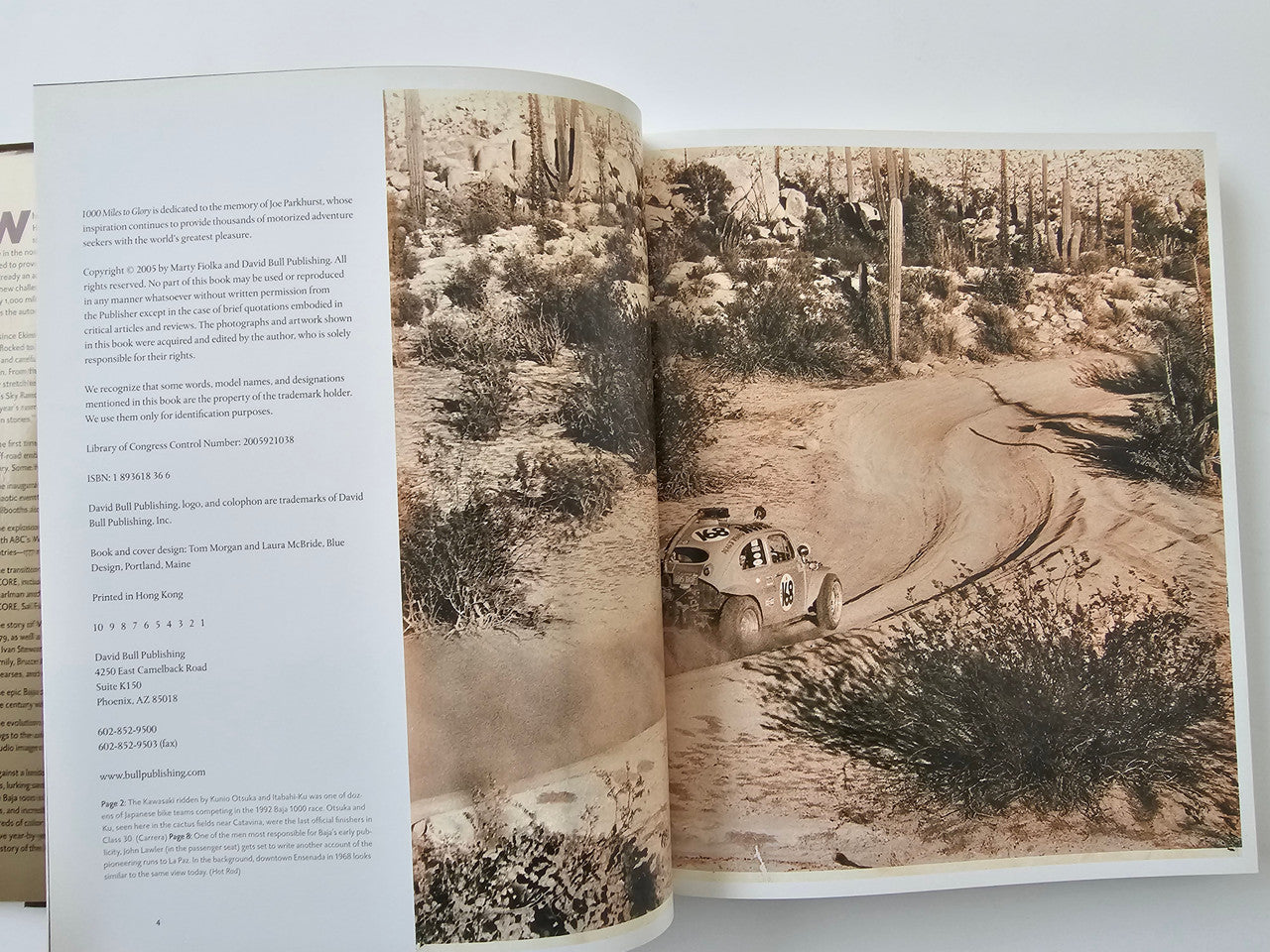 Opened book spread with sepia desert landscape photos and winding track details.