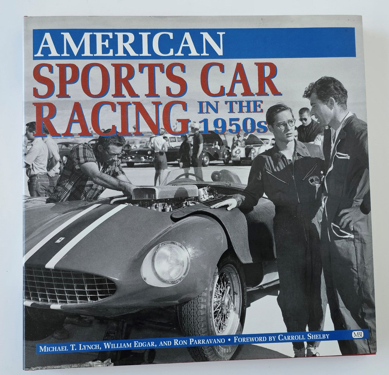 Book cover with blue and red title text over a vintage sports car racing photo