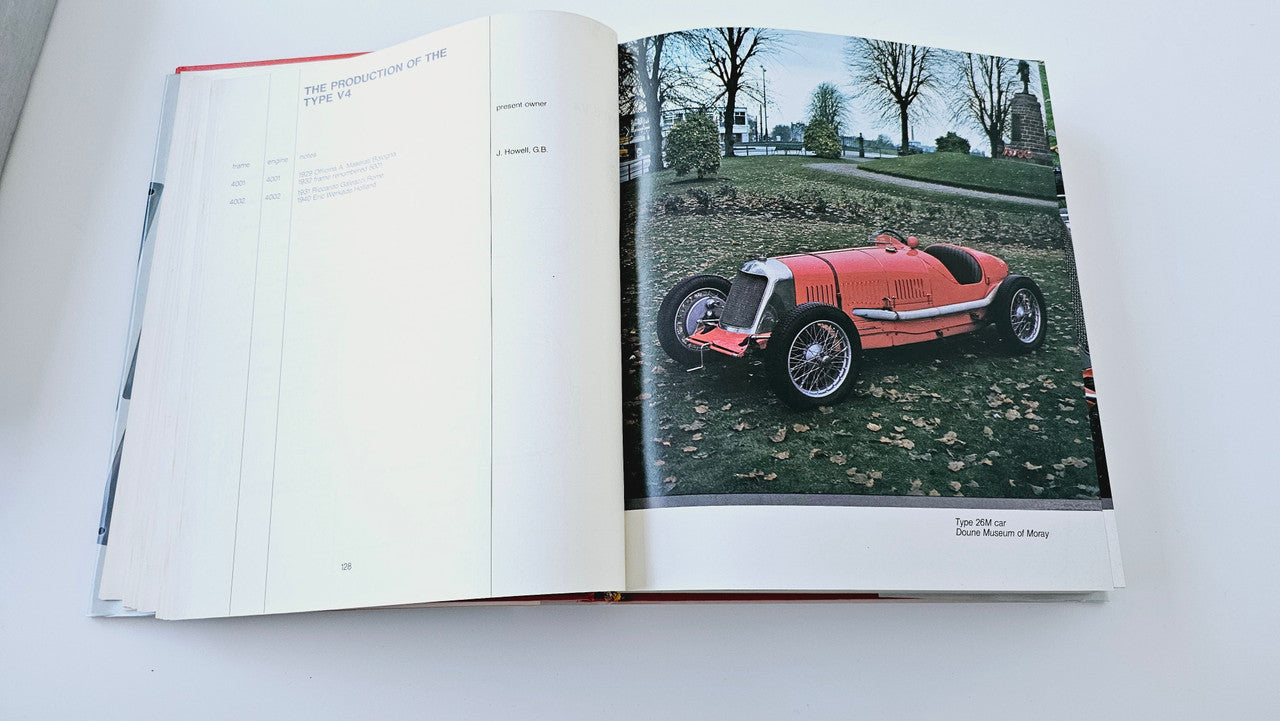Maserati history book open to a page with a red vintage car photo