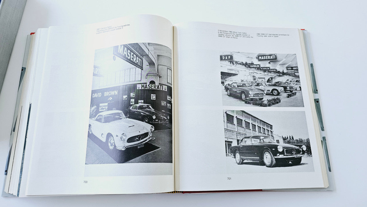 Maserati history book open to vintage vehicle photo pages