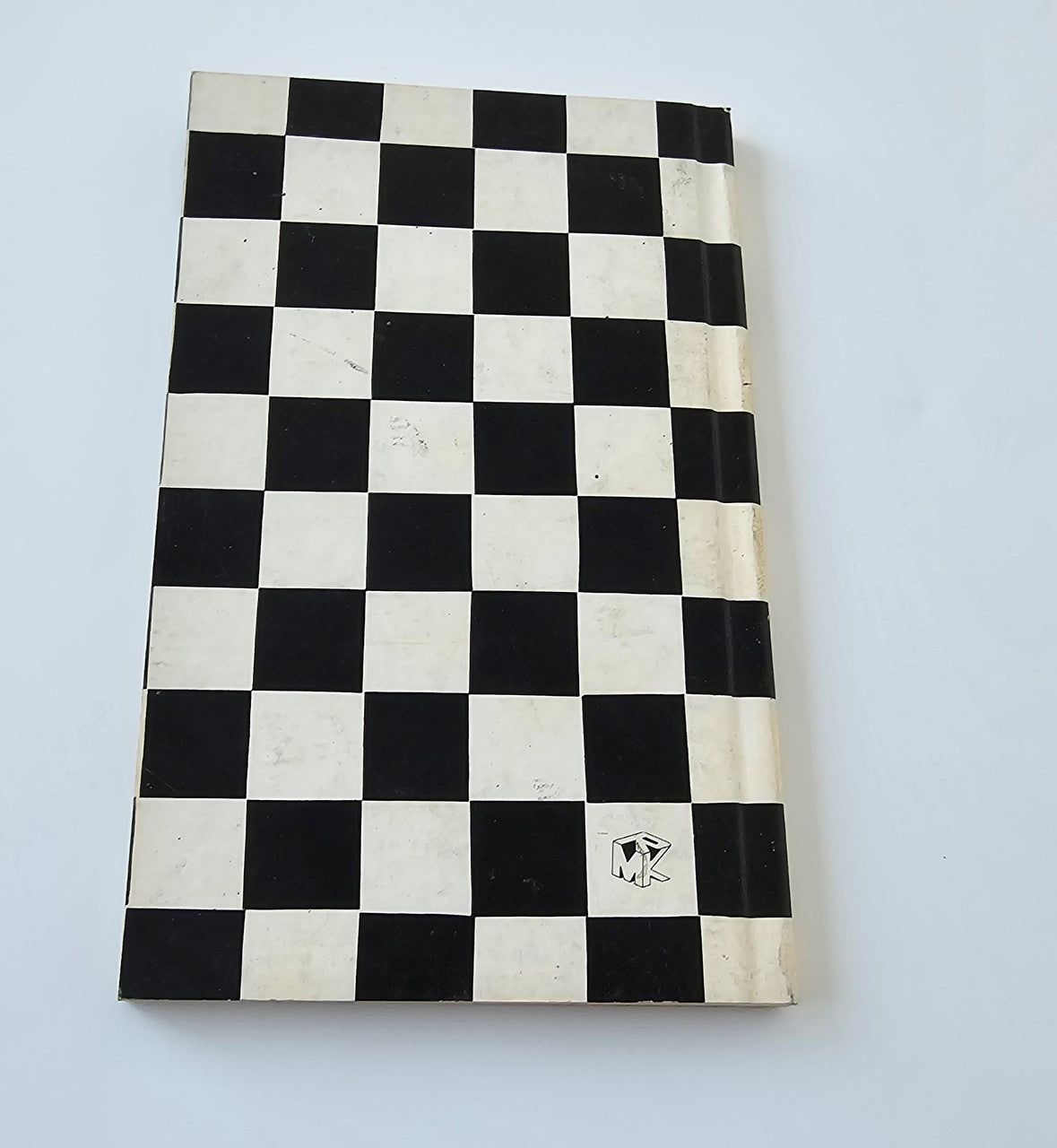 Motorsport book cover with black-and-white checkerboard pattern and small emblem.