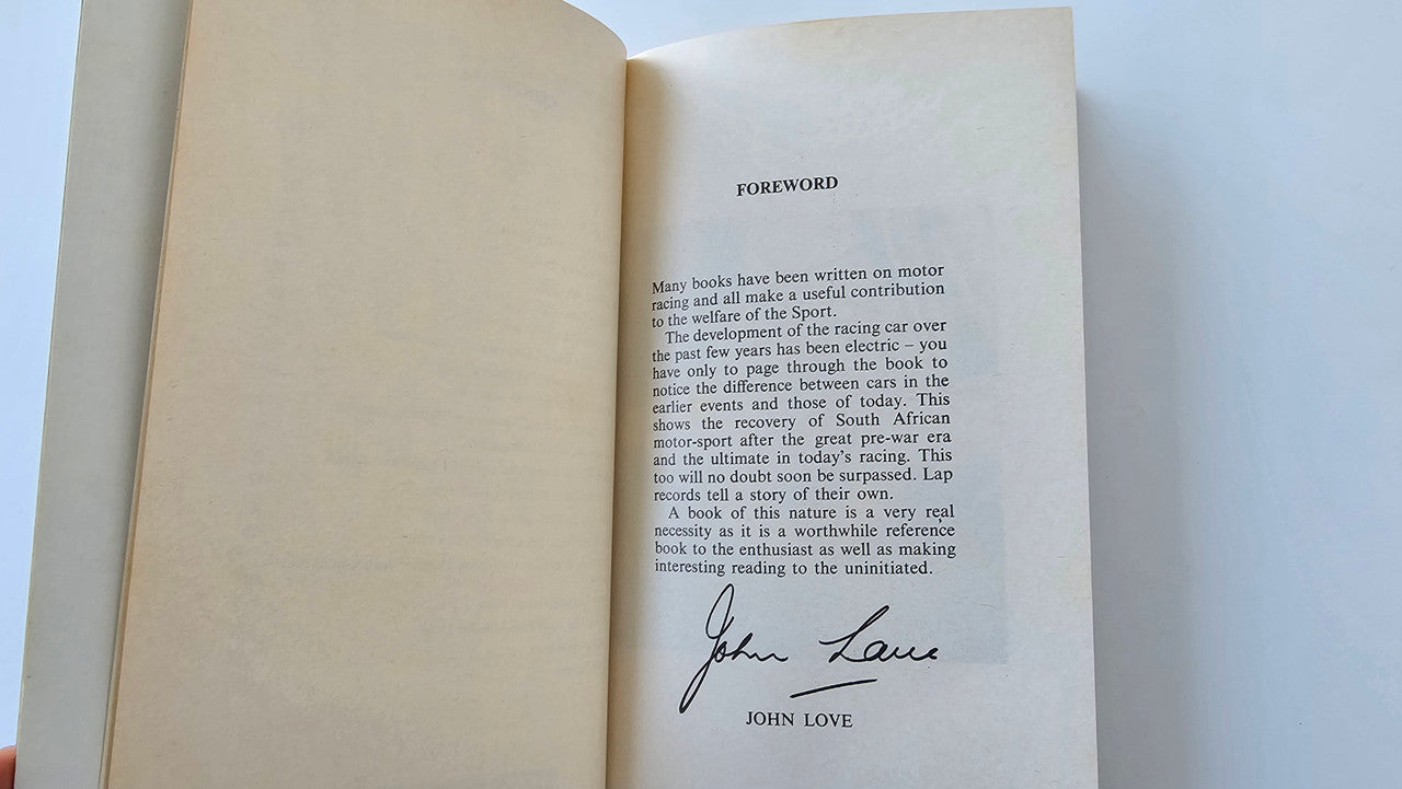Motorsport book open to the foreword page with a handwritten signature at bottom.