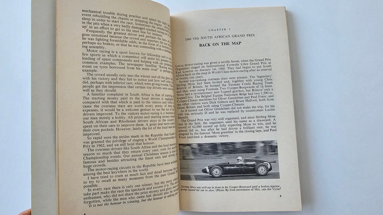 Motorsport book open to pages of text with a small racecar photo near the bottom.