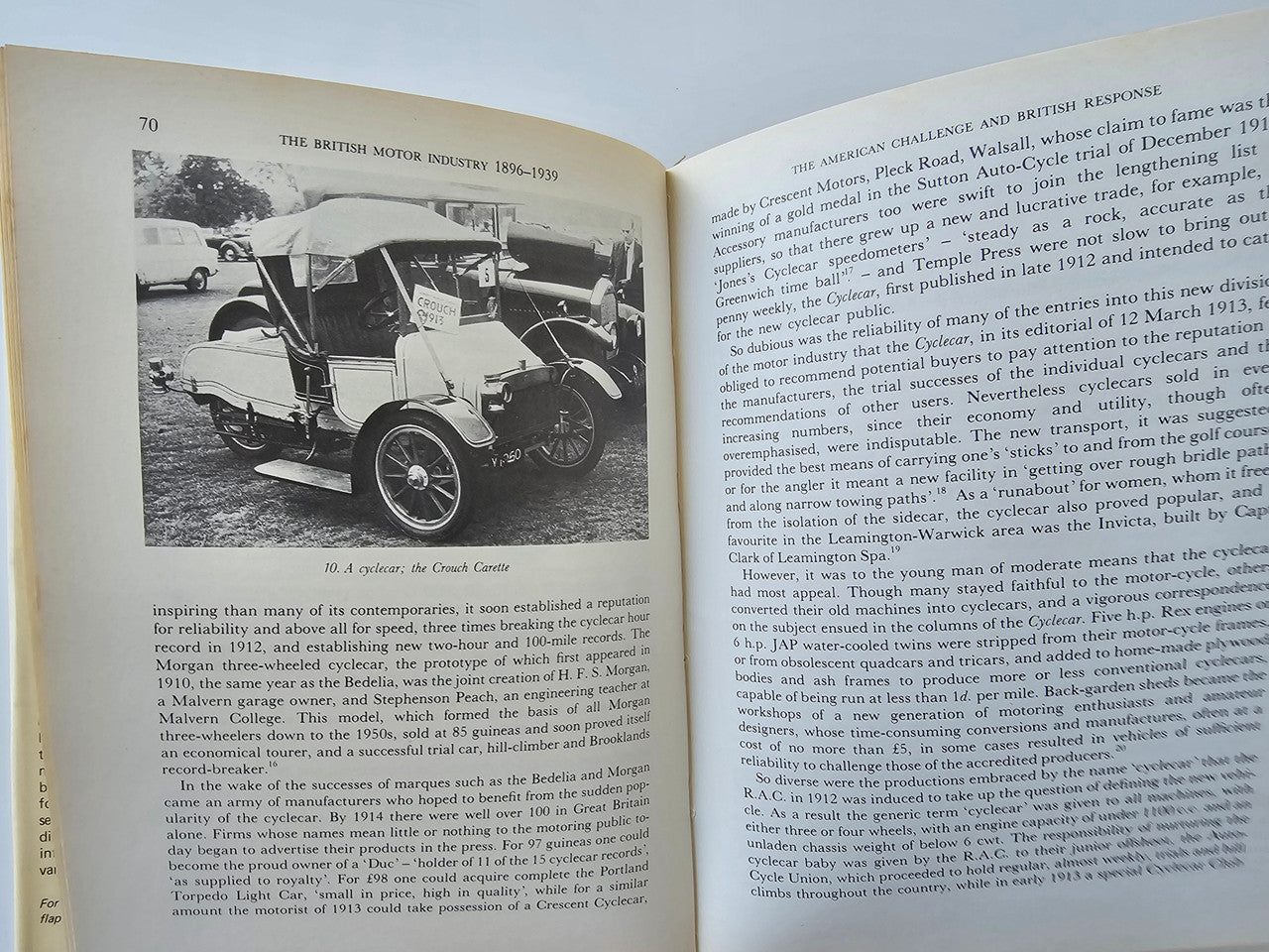 Open book with black-and-white photos of vintage cars and dense historical text