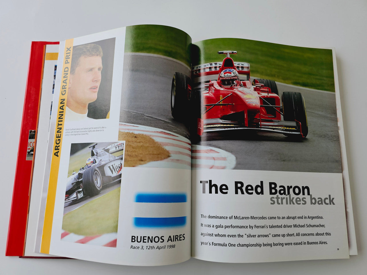 Open Formula One book spread with red race car photo and race caption text