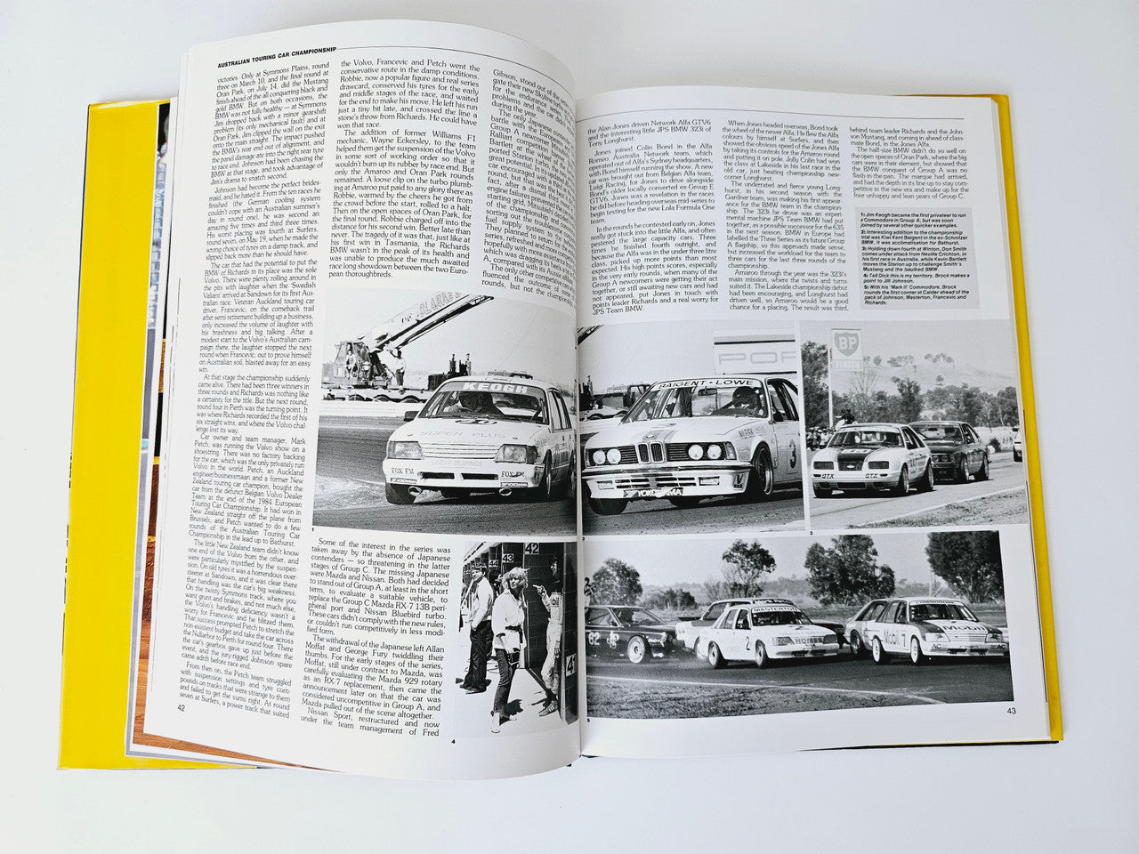 Open motoring magazine with black-and-white car photo collage across two pages