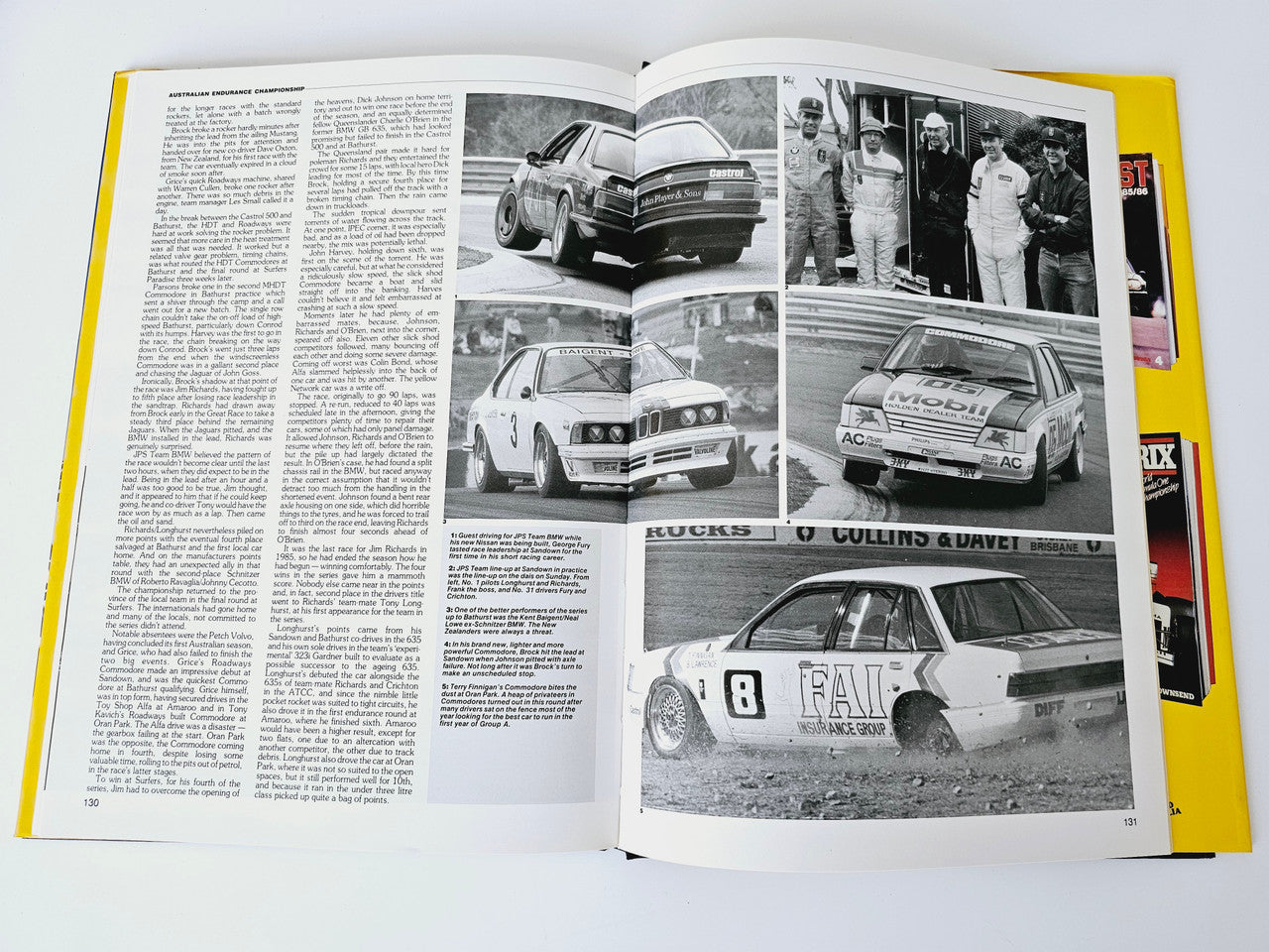 Open motoring magazine spread with black-and-white car photos and captions